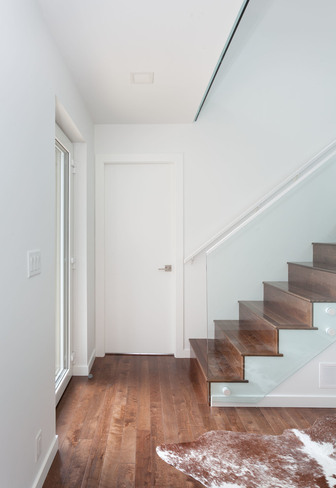 Idée de décoration pour une petite entrée minimaliste avec un couloir, un mur blanc, un sol en bois brun et un sol marron.