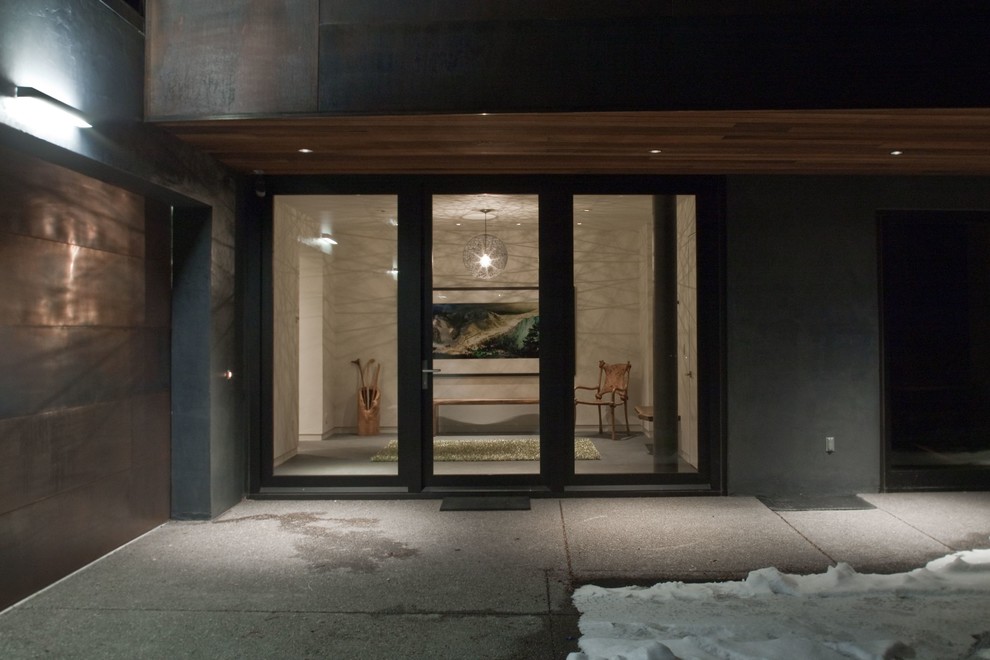 Esempio di un grande ingresso o corridoio minimal con pareti grigie, pavimento in cemento e una porta in metallo