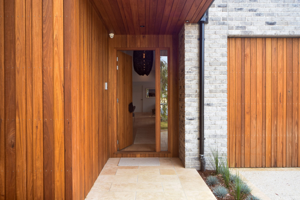 This is an example of a large modern hallway in Other with white walls, medium hardwood flooring, a single front door, a dark wood front door and brown floors.