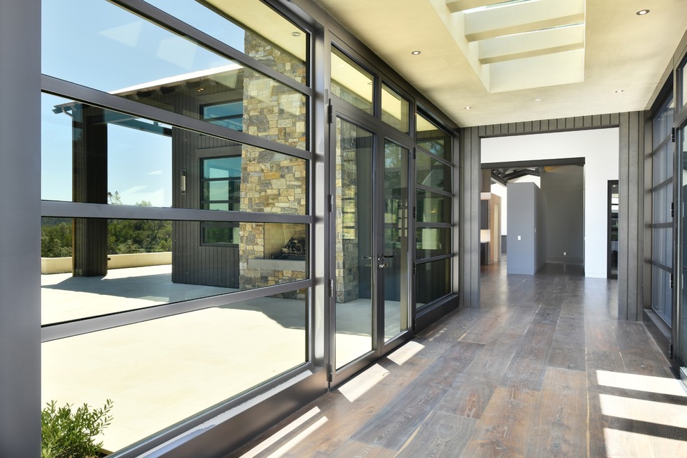 Foto de puerta principal moderna de tamaño medio con suelo de madera en tonos medios, puerta doble, puerta de vidrio y suelo marrón