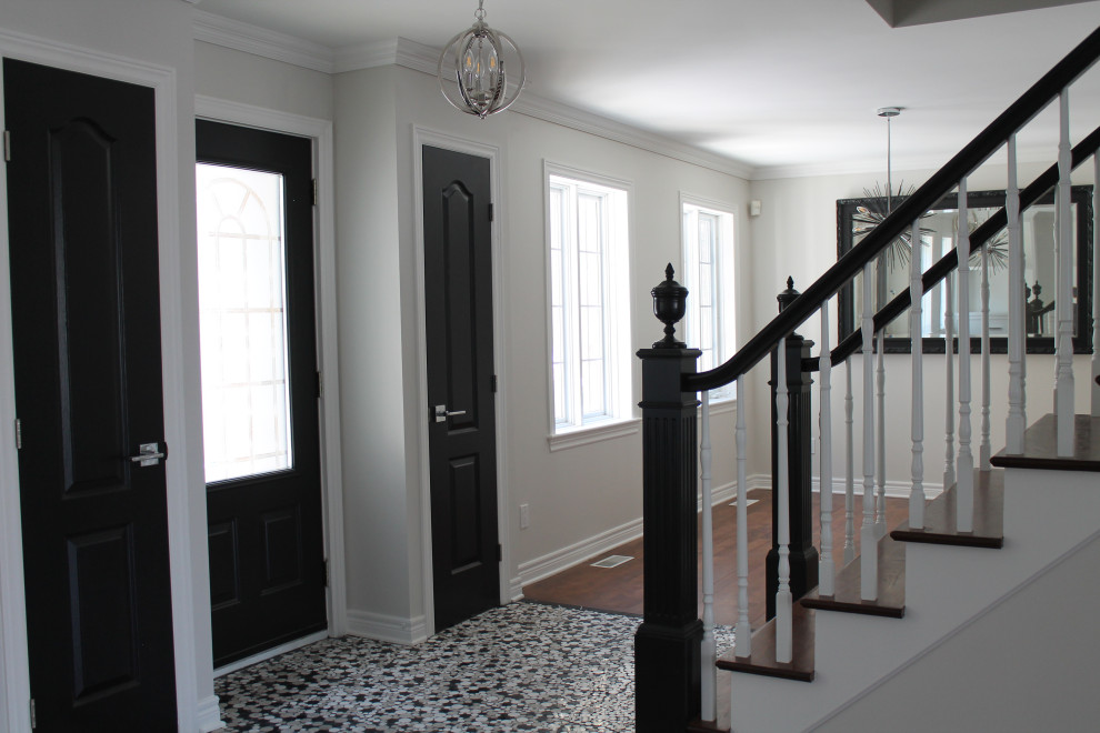 На фото: входная дверь среднего размера в стиле неоклассика (современная классика) с серыми стенами, мраморным полом, одностворчатой входной дверью, черной входной дверью и черным полом с