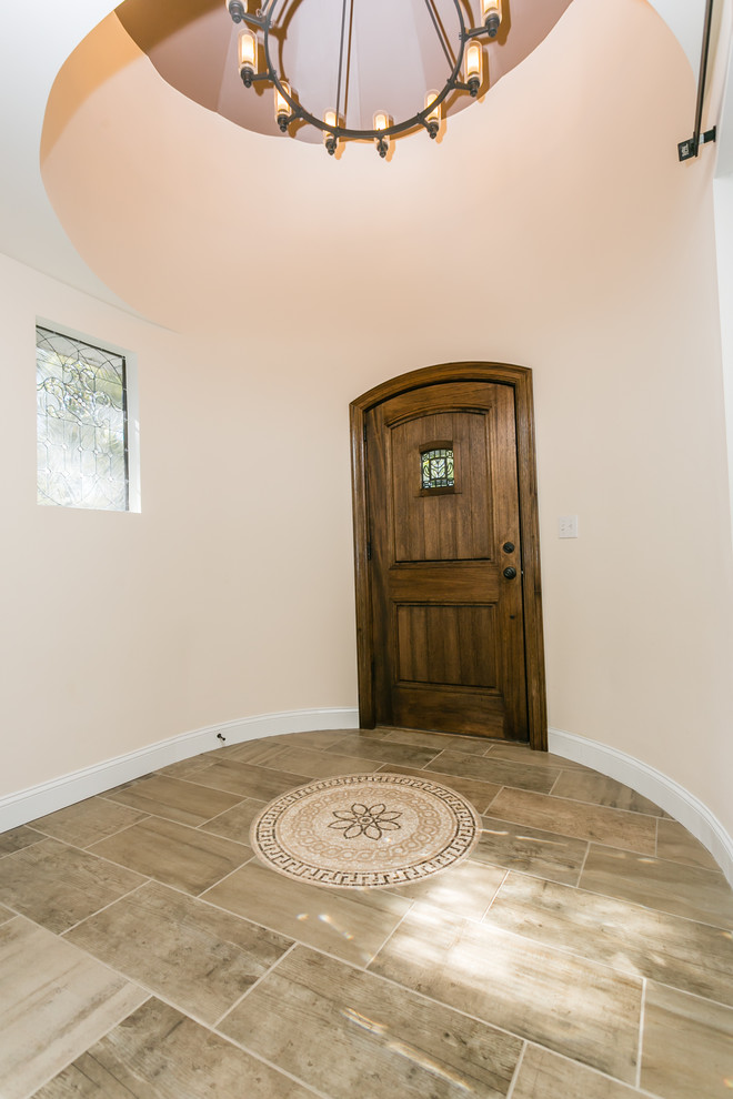 Mediterranes Foyer mit beiger Wandfarbe, Keramikboden, Einzeltür und dunkler Holzhaustür in St. Louis
