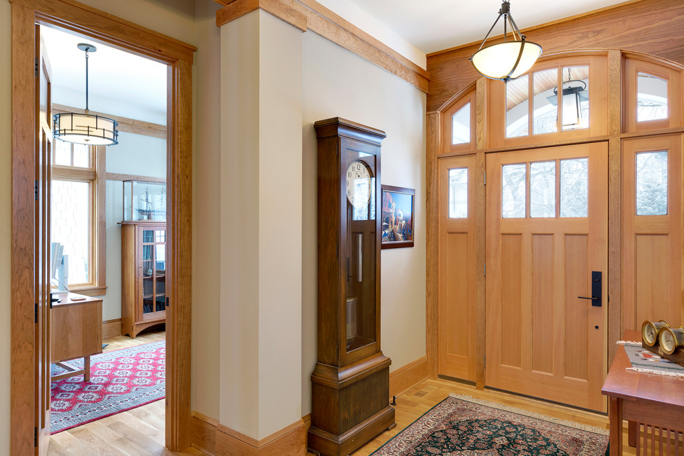 Cette photo montre une grande entrée chic avec un mur beige, un sol en bois brun, une porte simple, une porte en bois brun et un couloir.