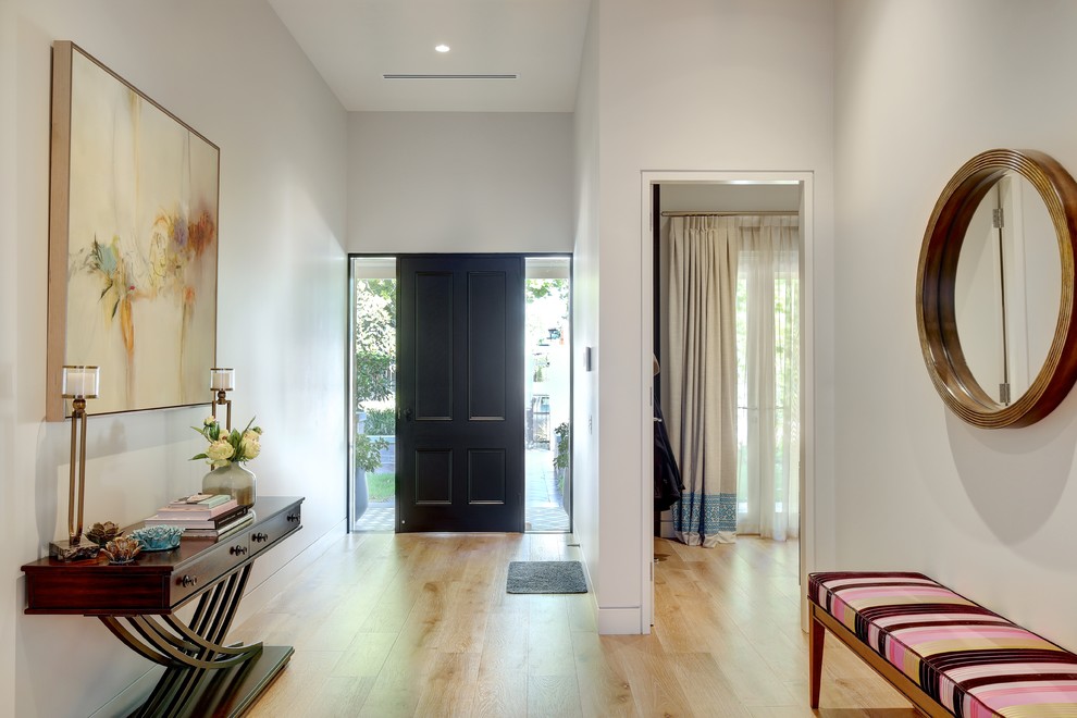 На фото: фойе среднего размера в современном стиле с белыми стенами, светлым паркетным полом, одностворчатой входной дверью, черной входной дверью и коричневым полом
