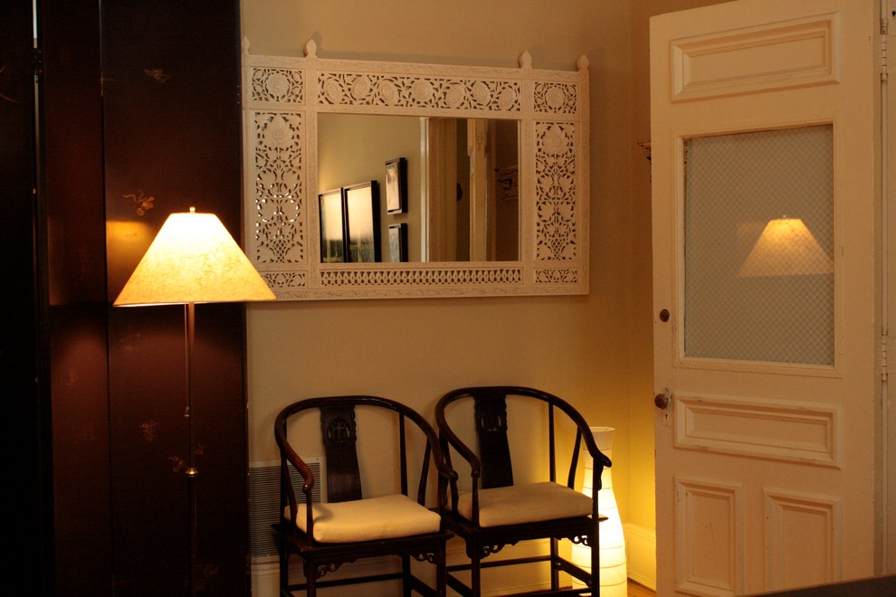 Aménagement d'un petit hall d'entrée éclectique avec un mur beige, un sol en bois brun, une porte simple et une porte blanche.