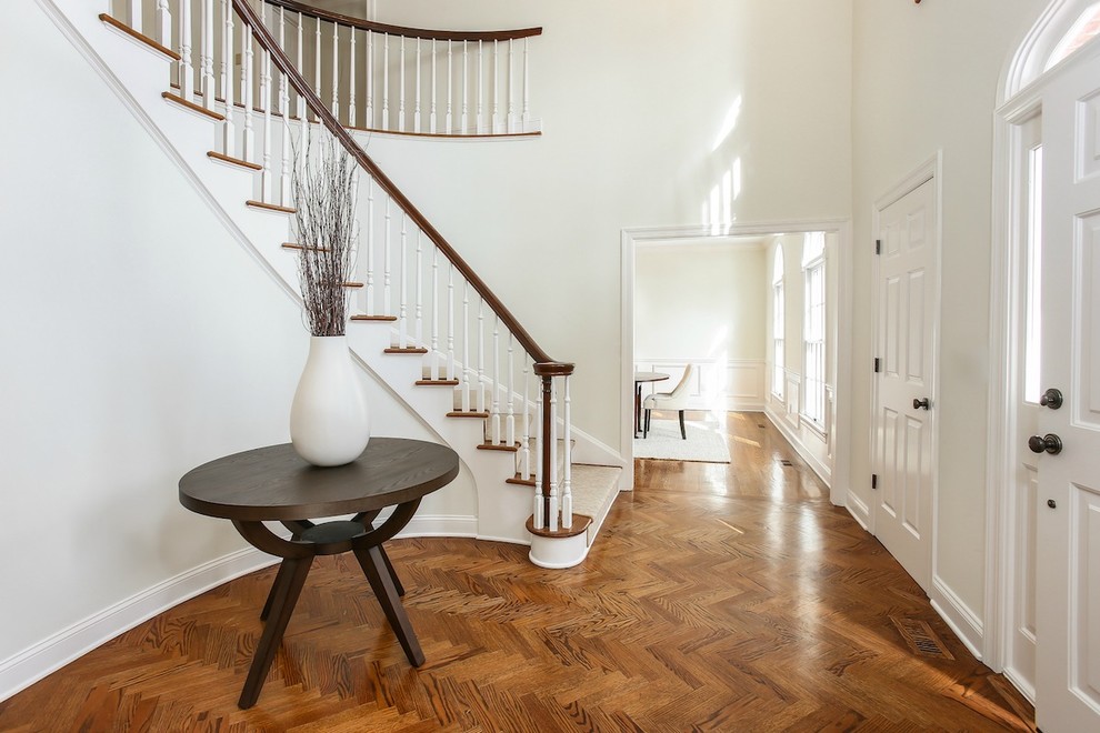 Large transitional medium tone wood floor and brown floor entryway photo in New York with white walls and a white front door