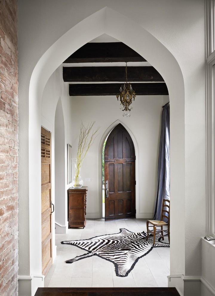 Idée de décoration pour un vestibule bohème avec un mur blanc, une porte simple, une porte en bois foncé et un sol blanc.