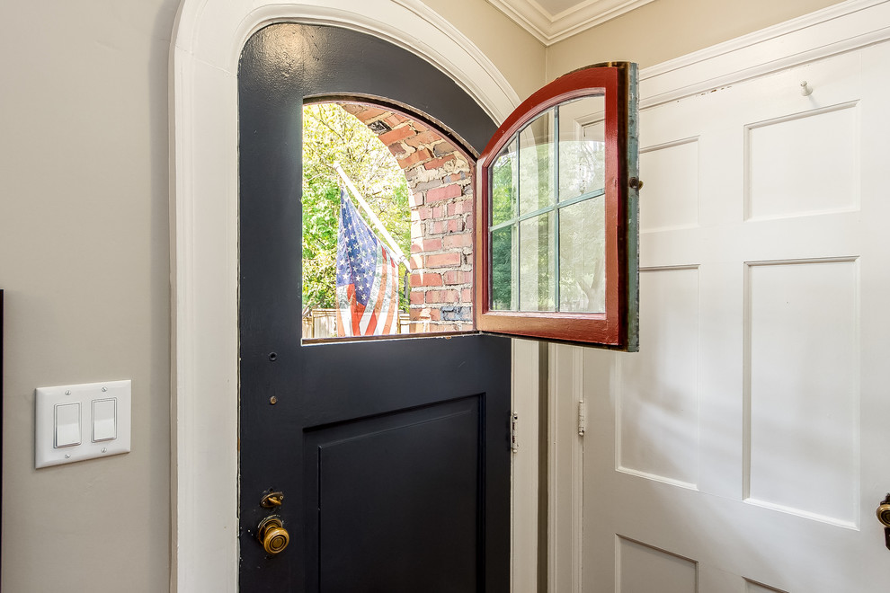 Réalisation d'une petite porte d'entrée tradition avec un mur beige, parquet clair, une porte hollandaise et une porte noire.