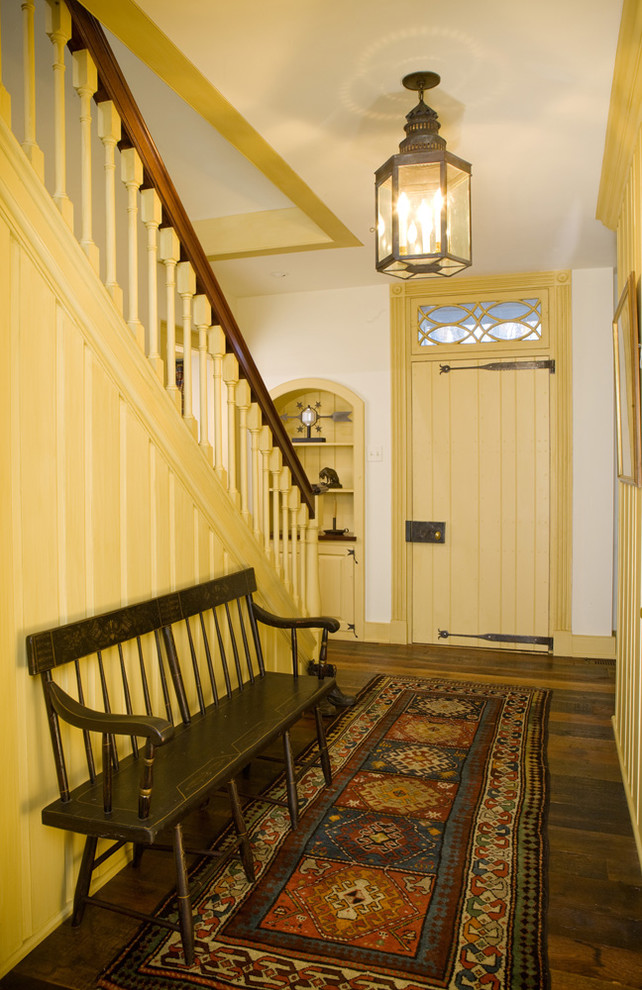 Réalisation d'une entrée champêtre de taille moyenne avec un couloir, un mur blanc, une porte simple, une porte jaune et un sol en bois brun.