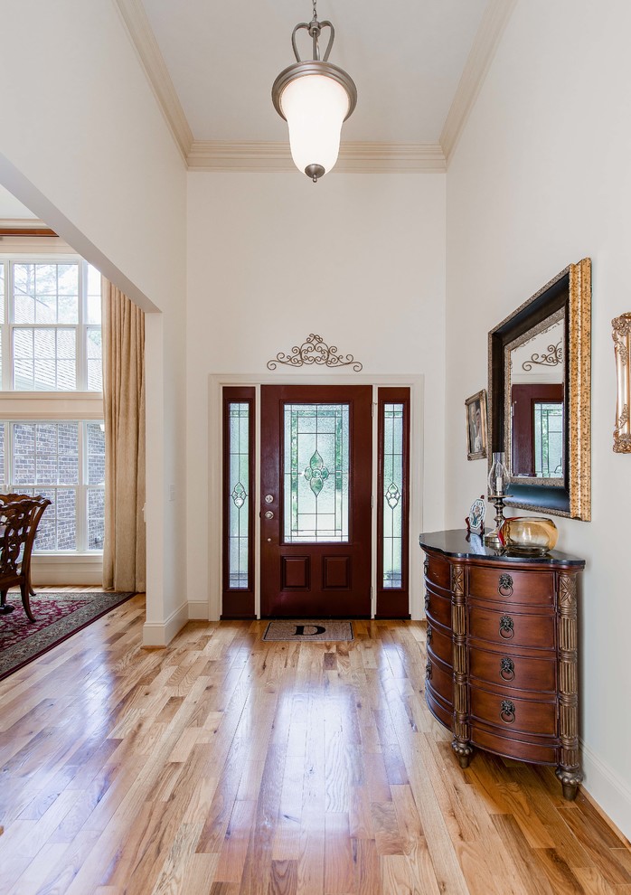 Klassische Haustür mit weißer Wandfarbe, hellem Holzboden, Einzeltür, dunkler Holzhaustür und beigem Boden in Charlotte
