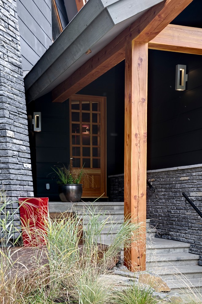 Foto di una porta d'ingresso minimal di medie dimensioni con pareti nere, pavimento in cemento, una porta singola, una porta in legno chiaro e pavimento grigio