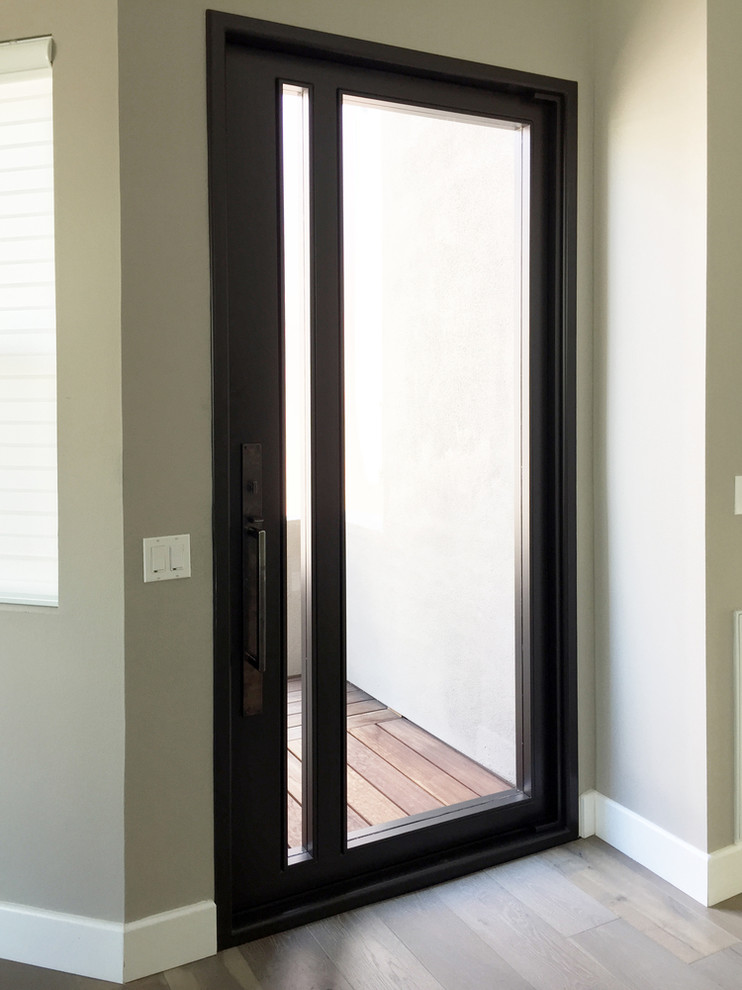 Große Moderne Haustür mit hellem Holzboden, Drehtür, beiger Wandfarbe und Haustür aus Metall in San Diego