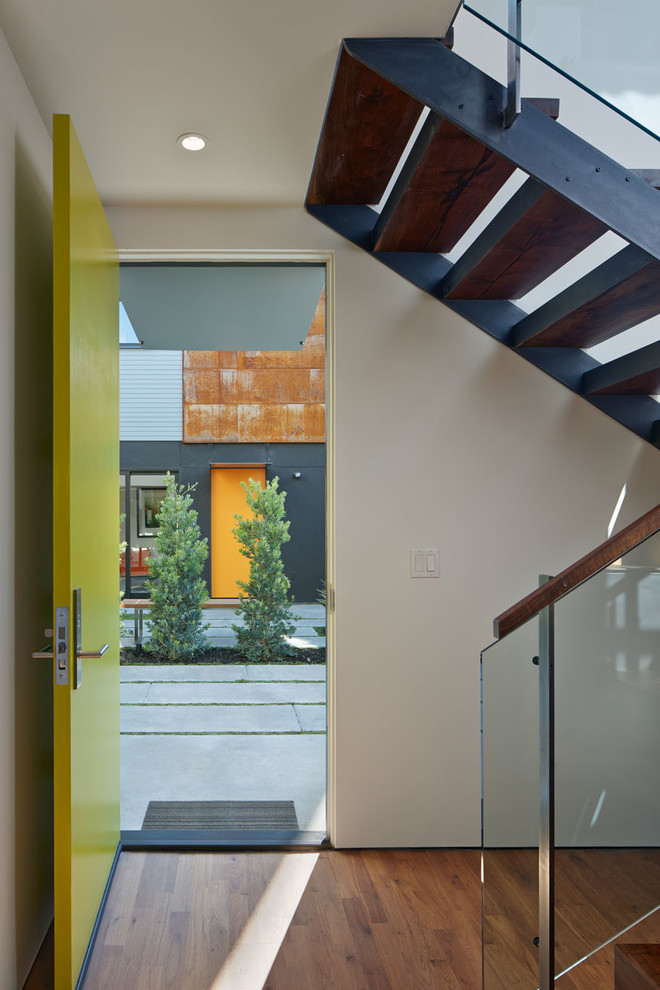 Foto på en liten funkis ingång och ytterdörr, med vita väggar, mellanmörkt trägolv, en enkeldörr och en grön dörr
