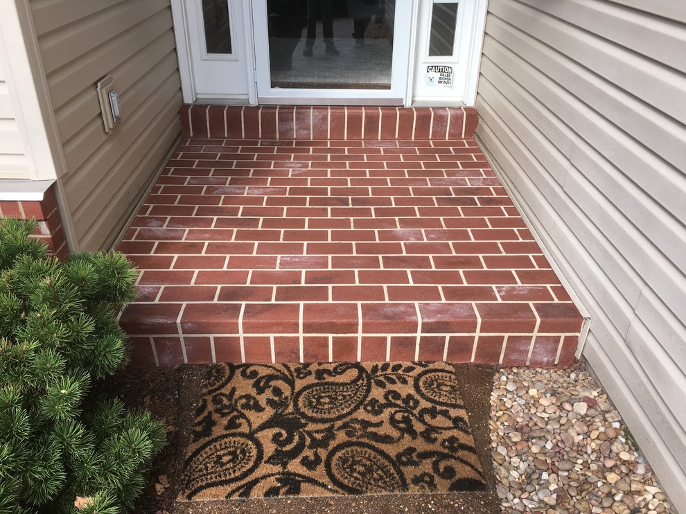 Example of a small classic brick floor entryway design in St Louis with beige walls and a white front door