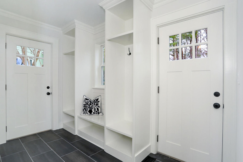Example of a mid-sized country porcelain tile and black floor mudroom design in New York with white walls and a black front door