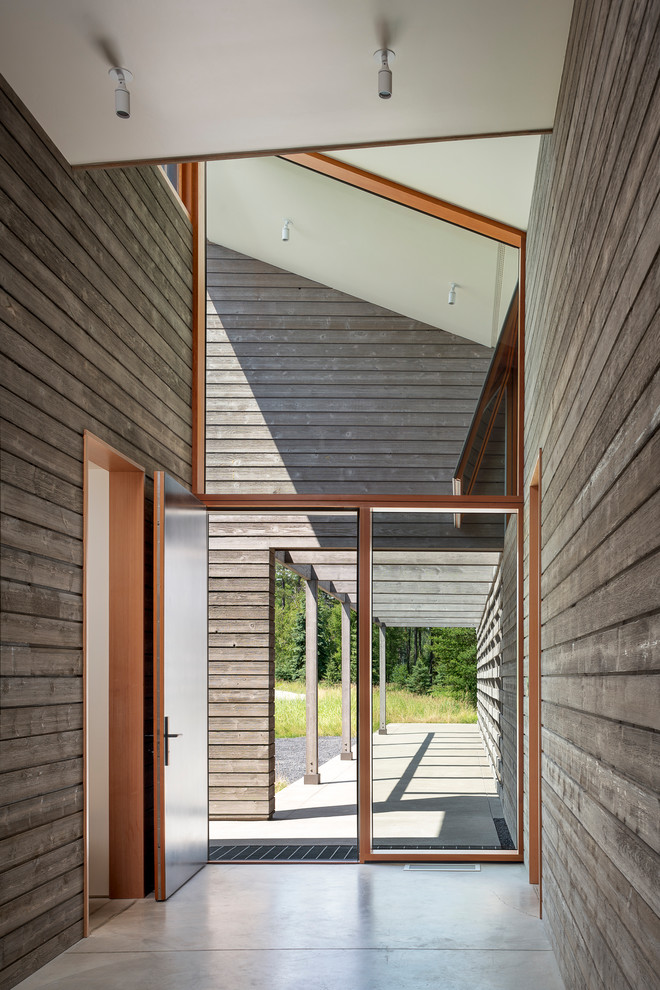 Aménagement d'un vestibule contemporain de taille moyenne avec un mur gris, sol en béton ciré, une porte simple, une porte en bois clair et un sol gris.