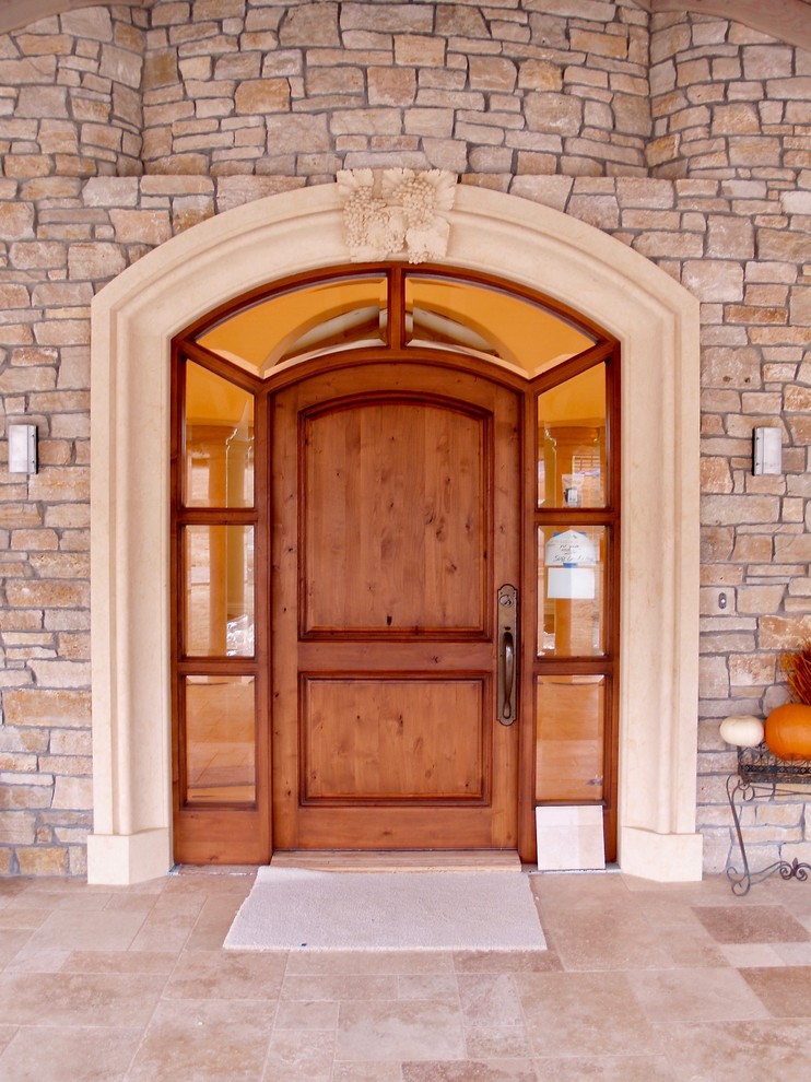 Aménagement d'une porte d'entrée classique avec une porte en bois brun et un sol beige.