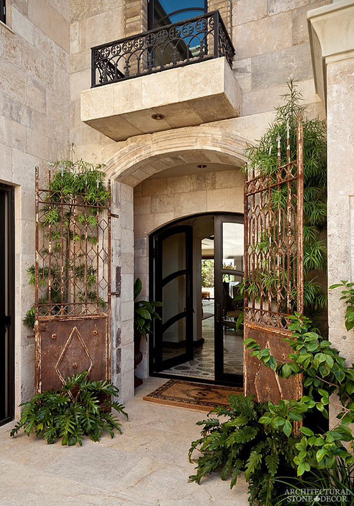 Foto de puerta principal mediterránea grande con paredes grises, suelo de piedra caliza y puerta doble