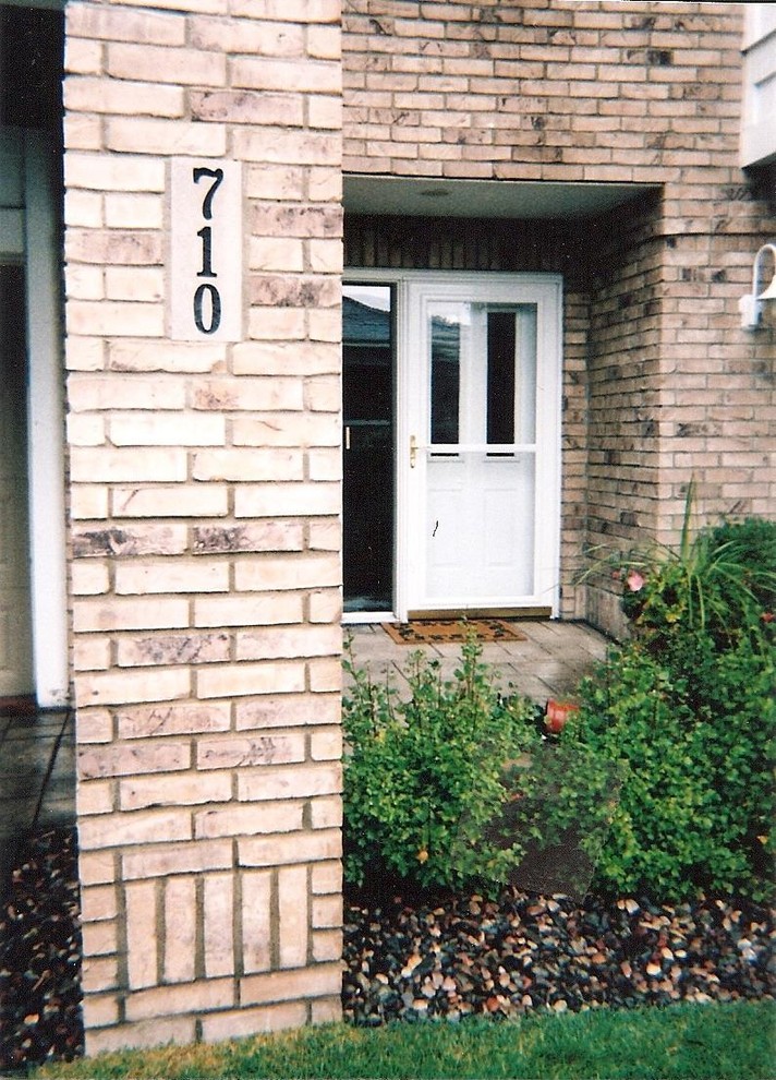 Immagine di una porta d'ingresso di medie dimensioni con pareti marroni, pavimento in cemento, una porta singola e una porta bianca