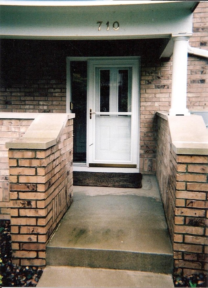 На фото: входная дверь среднего размера с коричневыми стенами, бетонным полом, одностворчатой входной дверью и белой входной дверью с