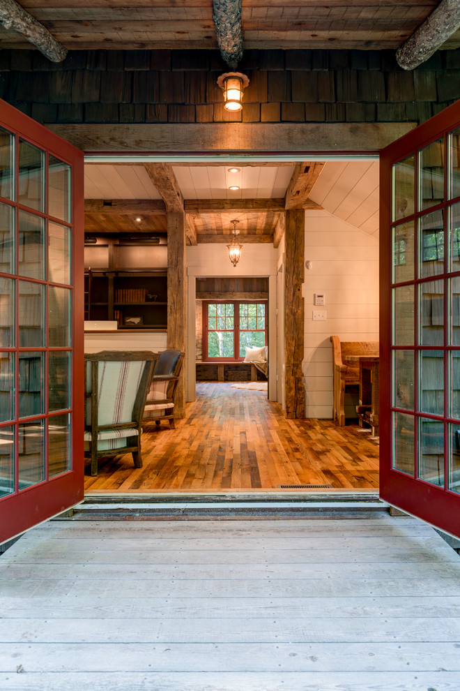 Ispirazione per un ingresso o corridoio stile rurale con pareti bianche, pavimento in legno massello medio, una porta a due ante e una porta rossa
