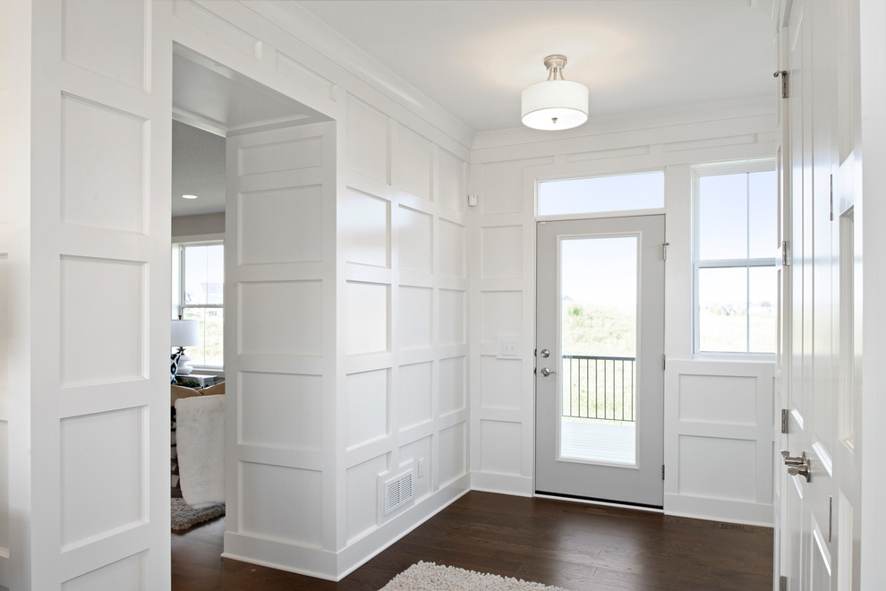 Foto di un grande ingresso tradizionale con pareti bianche, pavimento in legno massello medio, una porta singola e una porta grigia