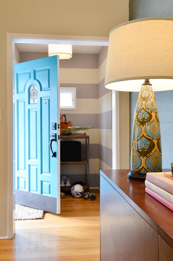 Cette photo montre une entrée chic avec un mur multicolore, un sol en bois brun, une porte simple et une porte bleue.