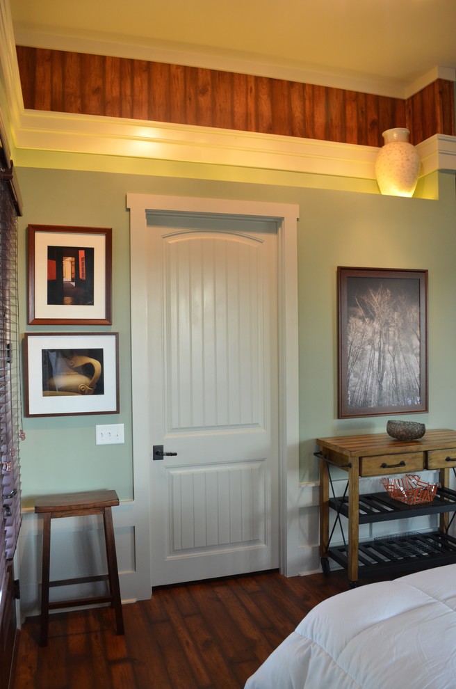 Cette image montre une petite porte d'entrée chalet avec un mur vert, un sol en bois brun, une porte double et une porte blanche.