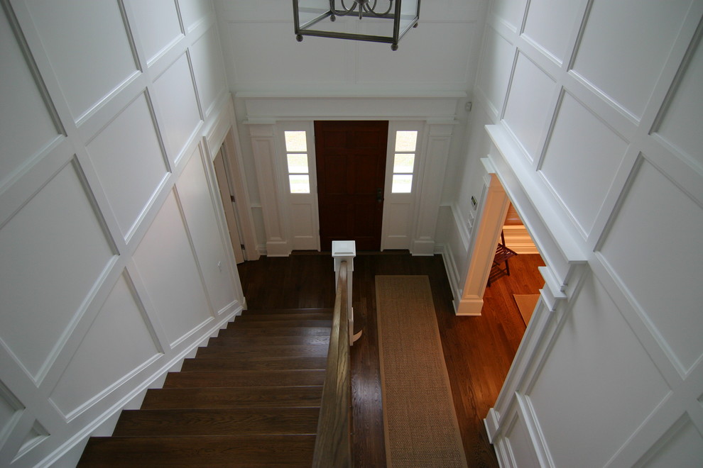 Ispirazione per un piccolo corridoio classico con pareti bianche, parquet scuro, una porta singola e una porta in legno scuro
