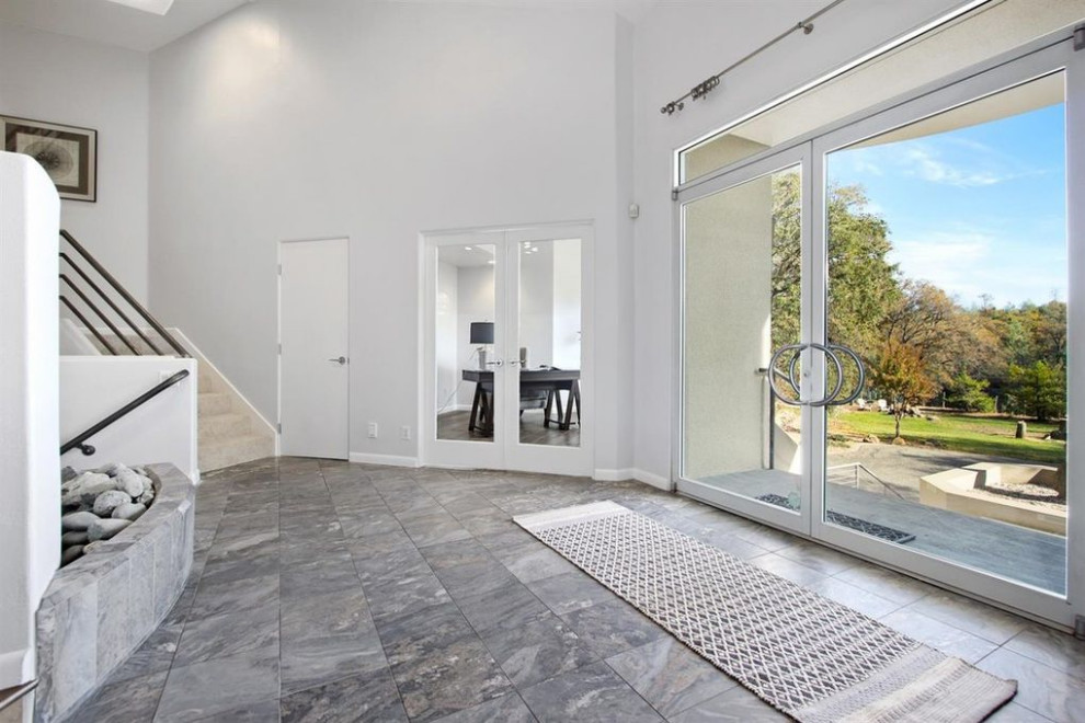 Photo of an expansive contemporary front door in Sacramento with white walls, marble flooring, a pivot front door, a glass front door and grey floors.