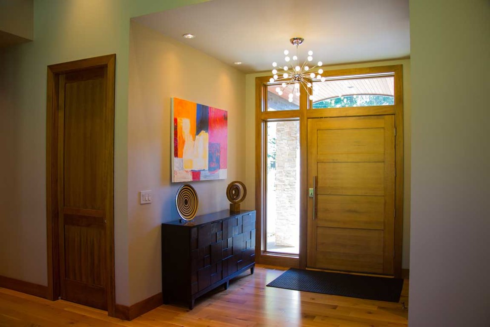 Cette photo montre un hall d'entrée tendance de taille moyenne avec un mur beige, un sol en bois brun, une porte simple et une porte en bois clair.