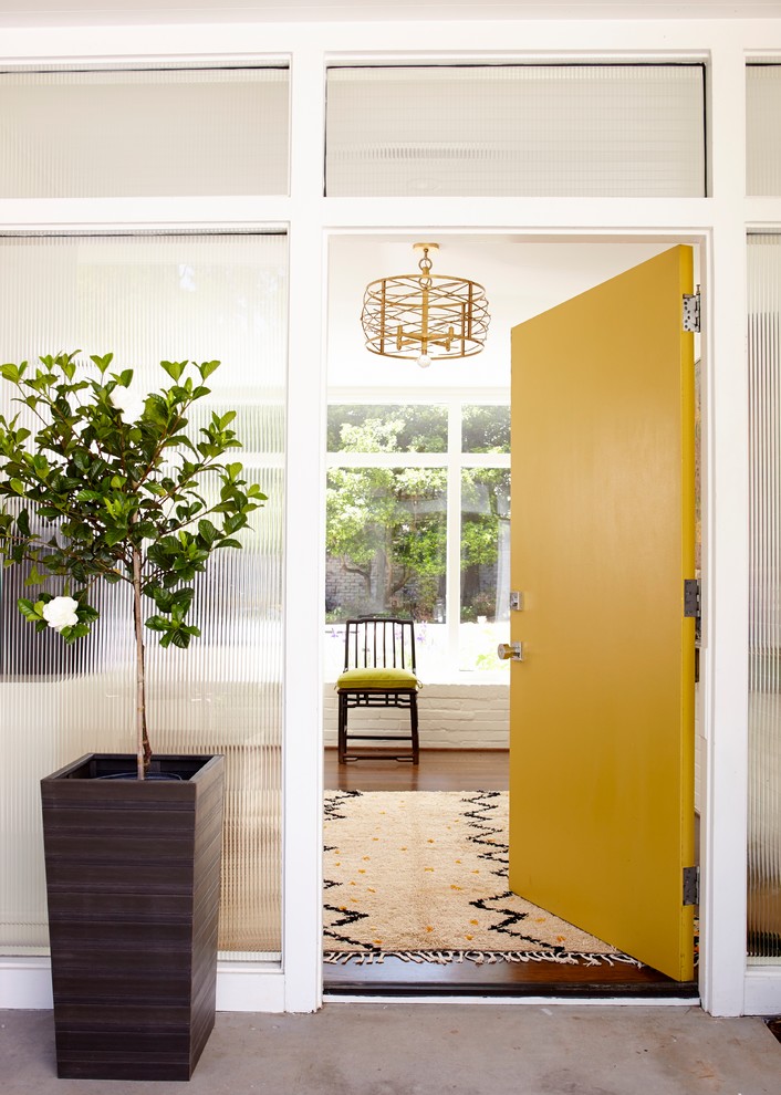 Idée de décoration pour une entrée design avec une porte jaune et une porte simple.