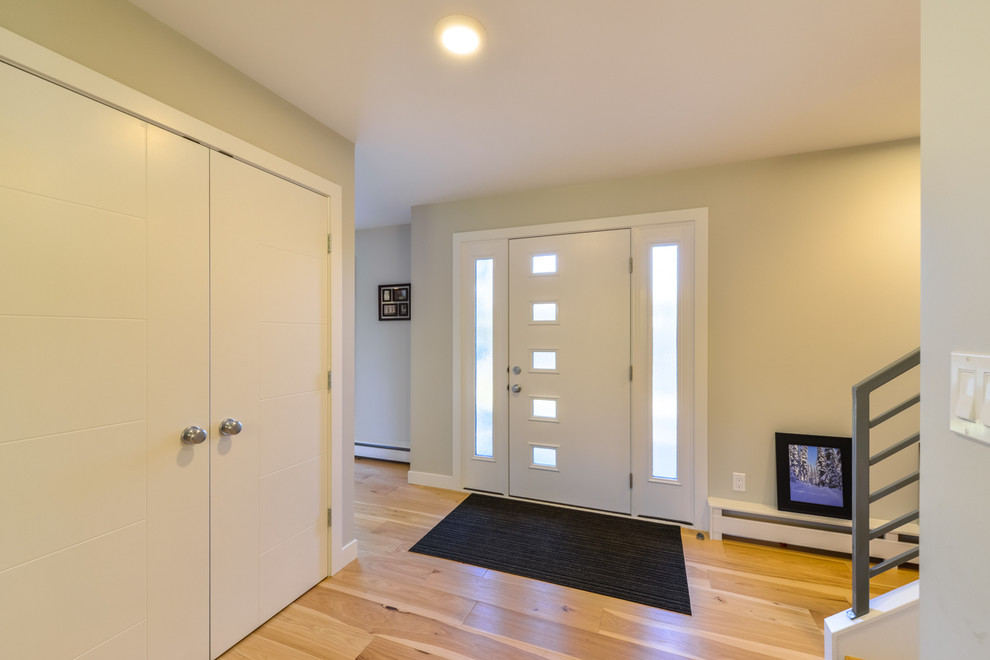 Esempio di un ingresso minimalista di medie dimensioni con pareti beige, parquet chiaro, una porta singola, una porta bianca e pavimento beige