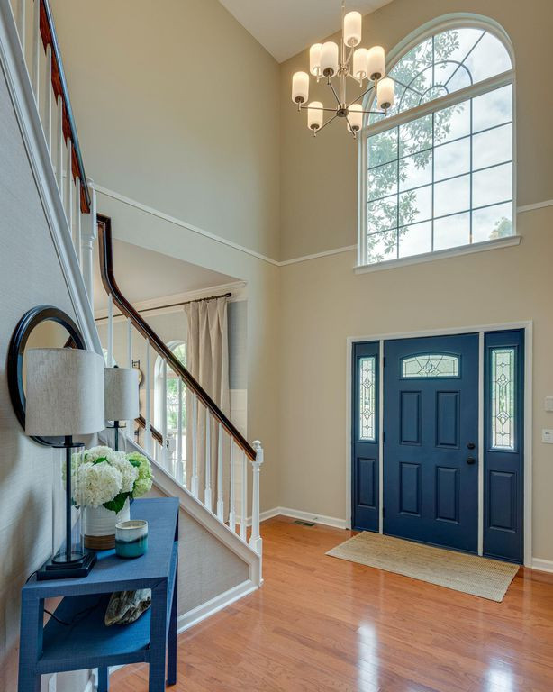 Geräumiges Klassisches Foyer mit beiger Wandfarbe, braunem Holzboden, Einzeltür, blauer Haustür und orangem Boden in Nashville