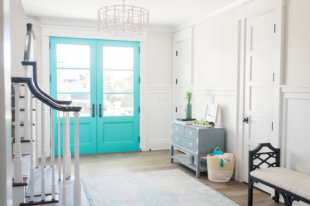 Ispirazione per un ingresso o corridoio stile marino con pareti bianche, pavimento in legno massello medio, una porta a due ante, una porta blu e pavimento marrone