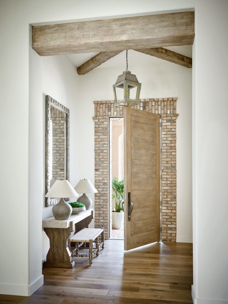 Foto di un ingresso o corridoio con pareti beige, pavimento in legno massello medio, una porta singola, una porta in legno chiaro, pavimento marrone e travi a vista