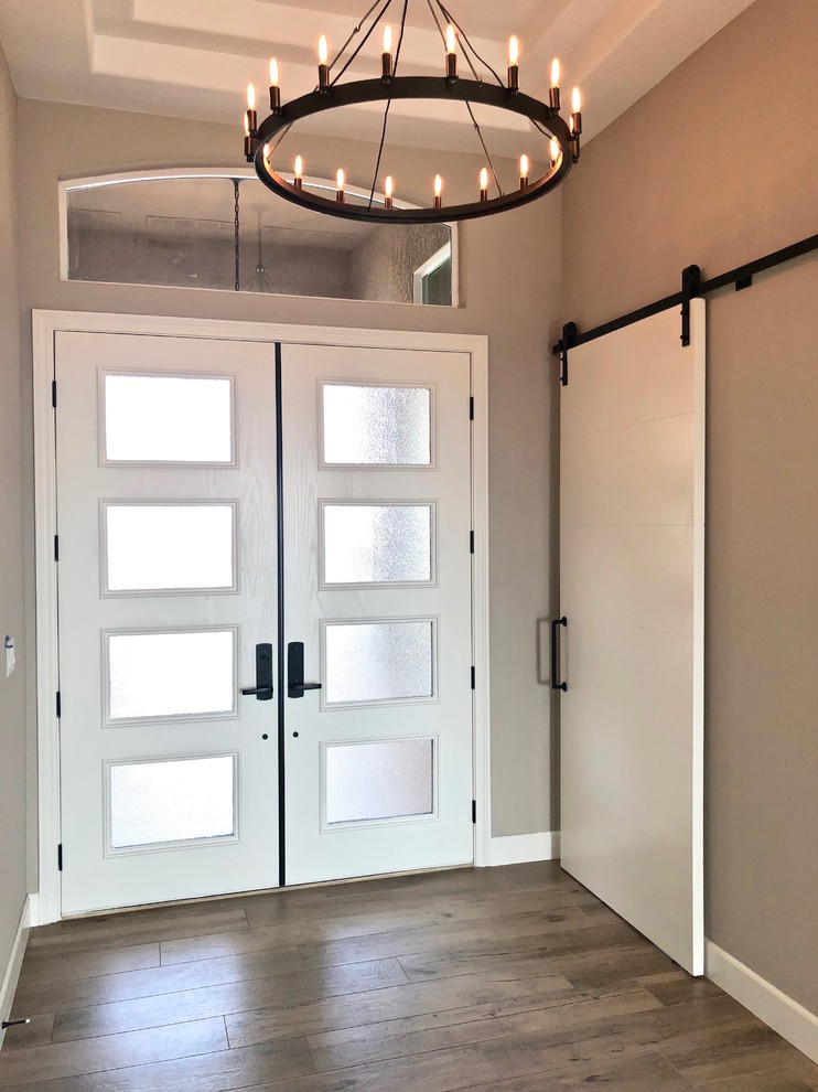 Idee per una porta d'ingresso mediterranea di medie dimensioni con pareti grigie, parquet scuro, una porta a due ante, una porta bianca e pavimento marrone
