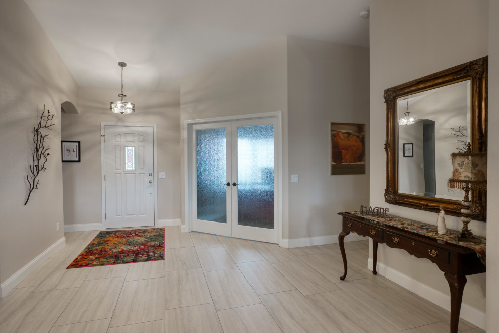 他の地域にあるお手頃価格の中くらいなトランジショナルスタイルのおしゃれな玄関ロビー (ベージュの壁、白いドア、ベージュの床) の写真
