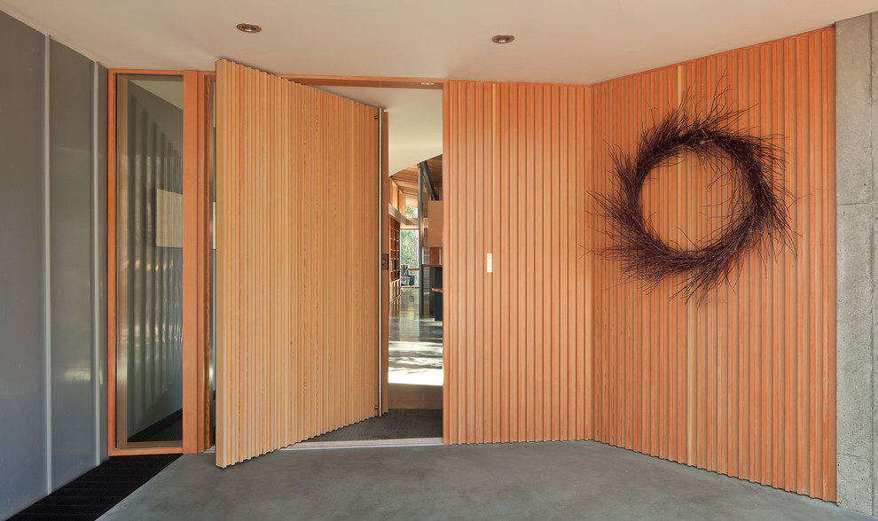 Mittelgroßes Modernes Foyer mit grauer Wandfarbe, Betonboden, Drehtür und hellbrauner Holzhaustür in Seattle