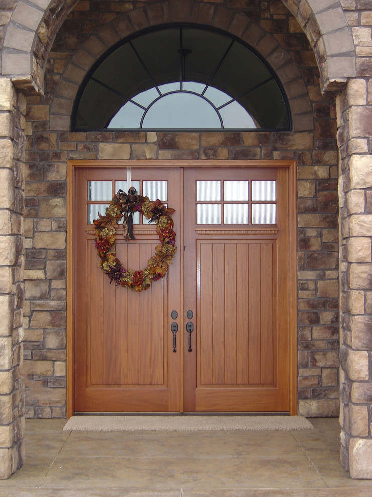 Пример оригинального дизайна: большая входная дверь в классическом стиле с коричневыми стенами, бетонным полом, двустворчатой входной дверью, входной дверью из дерева среднего тона и коричневым полом