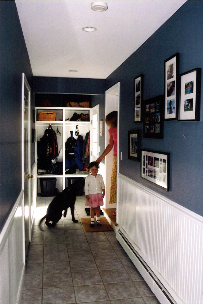 Cette image montre une entrée design avec un vestiaire, un mur bleu et un sol en carrelage de porcelaine.