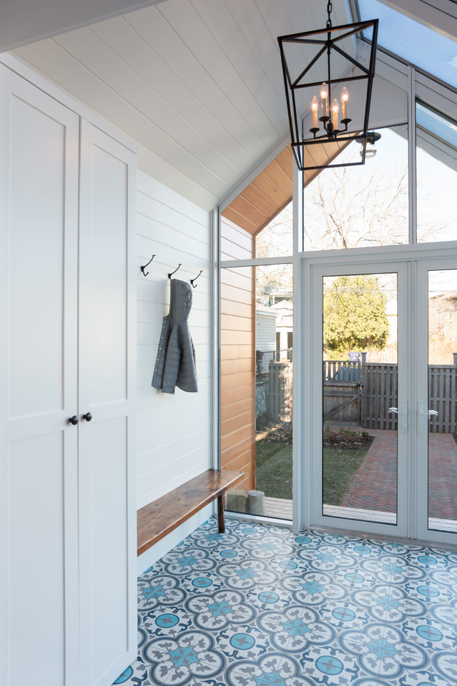 Cette image montre une petite entrée design avec un vestiaire, un mur blanc, une porte double et une porte en verre.