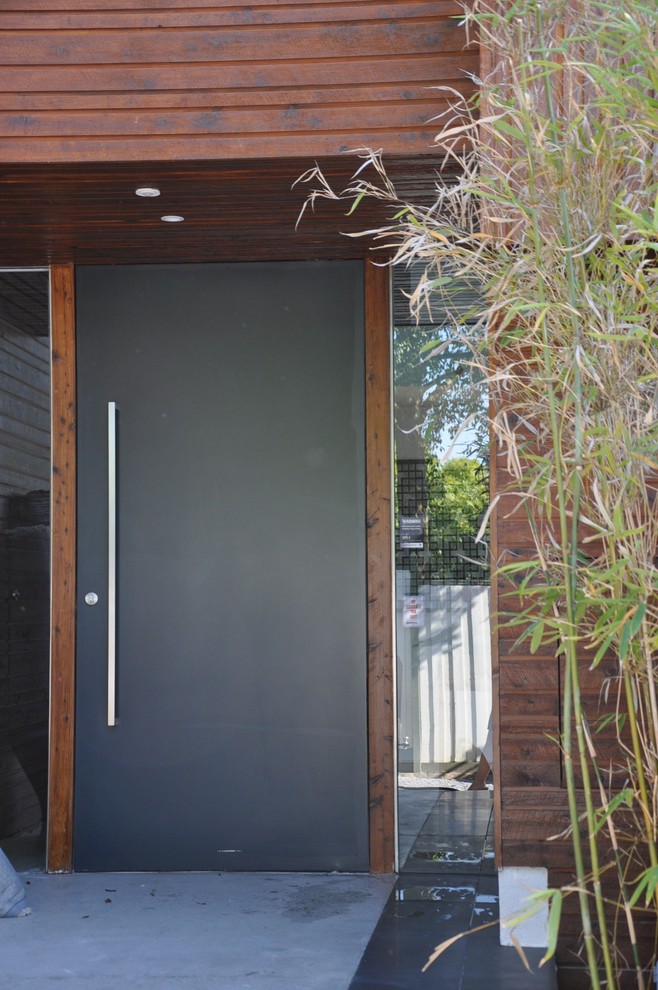 Réalisation d'une grande porte d'entrée design avec sol en béton ciré, une porte simple, une porte grise et un sol gris.