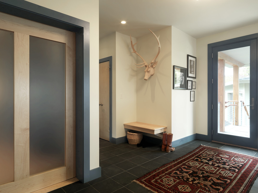 Ejemplo de entrada contemporánea con paredes beige, puerta simple, puerta de vidrio y suelo negro