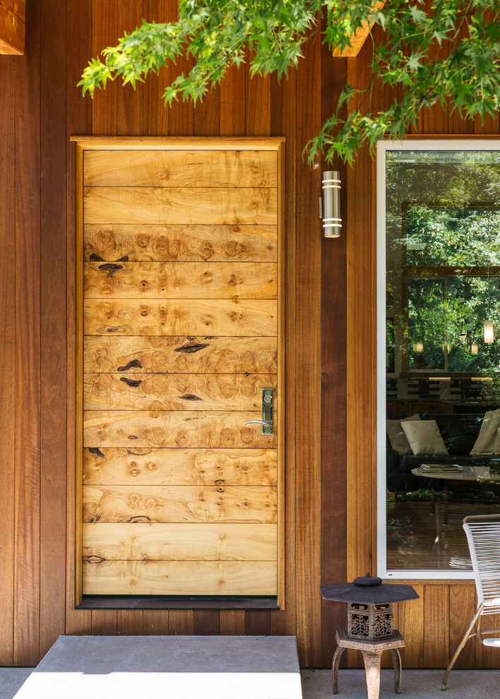 Foto di una porta d'ingresso moderna di medie dimensioni con una porta in legno chiaro, una porta singola, pareti marroni, pavimento in cemento e pavimento grigio