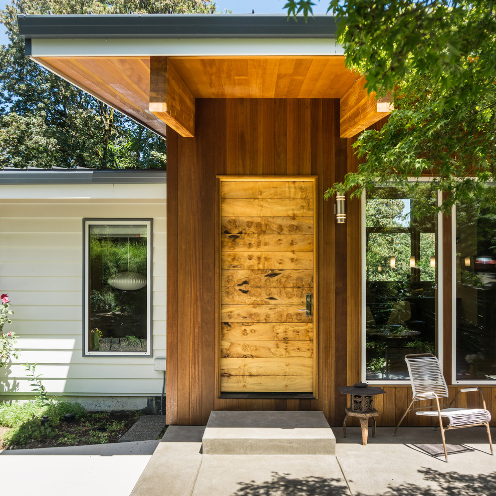 Cette image montre une porte d'entrée minimaliste de taille moyenne avec une porte en bois clair, une porte simple, un mur marron, sol en béton ciré et un sol gris.