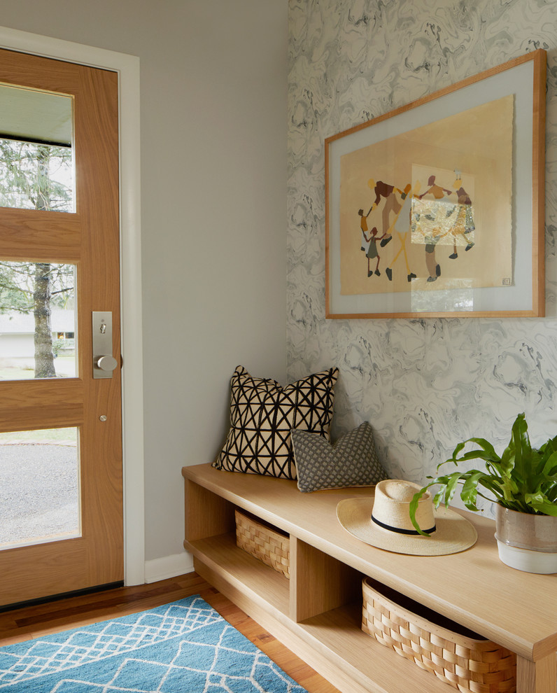 Idée de décoration pour un hall d'entrée tradition avec un mur gris, un sol en bois brun, une porte simple et un sol marron.
