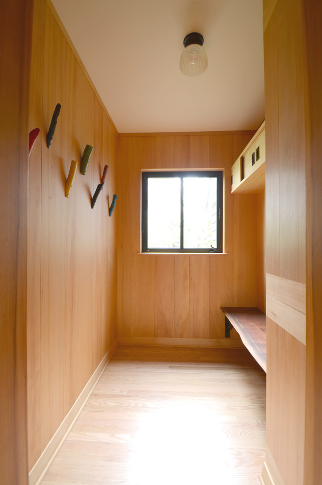 Cette photo montre une petite entrée tendance avec un vestiaire, un mur marron, parquet clair, une porte simple, une porte en bois clair et un sol marron.