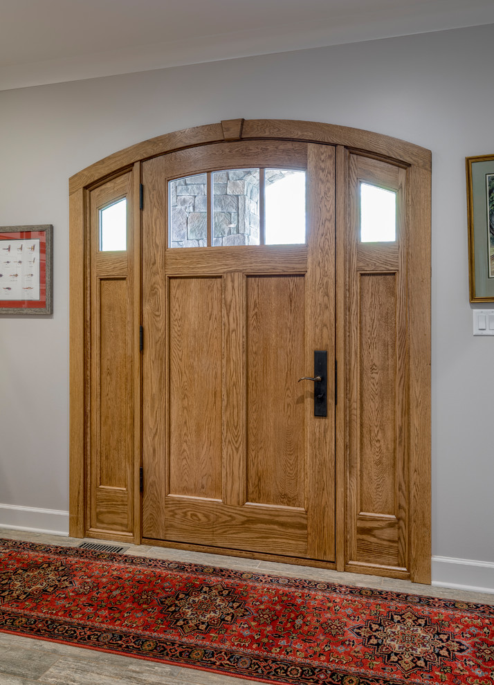Пример оригинального дизайна: входная дверь среднего размера в стиле кантри с коричневыми стенами, паркетным полом среднего тона, одностворчатой входной дверью, входной дверью из дерева среднего тона и коричневым полом