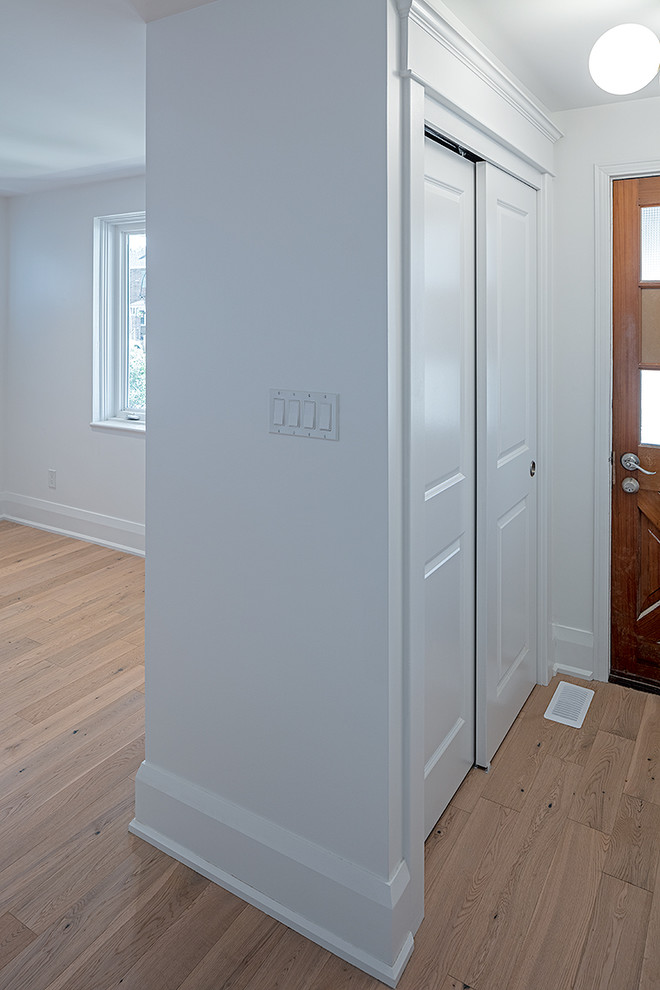 Kleines Klassisches Foyer mit weißer Wandfarbe, hellem Holzboden, Einzeltür, brauner Haustür und braunem Boden in Toronto